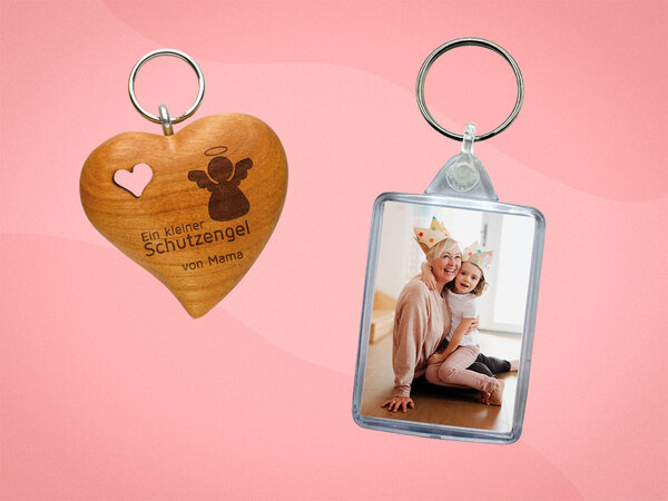 Herzförmiger Holzanhänger mit ausgestanztem Herz und persönlicher Gravur. Daneben ein Schlüsselanhänger aus Acryl mit Foto.